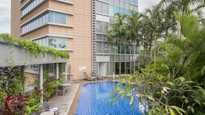 A modern building with a pool, surrounded by lush greenery and outdoor seating. - Park Avenue Rochester (Singapore)