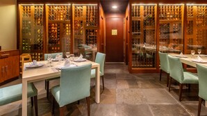 Una bodega con estanterías de vidrio para vinos y mesas dispuestas para cenar.