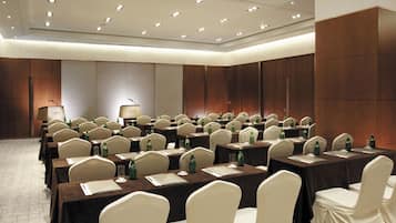 A conference room with multiple tables, chairs, and a podium.