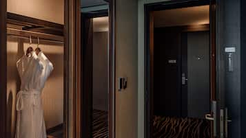 Ein Hotelzimmer mit Bademantel an einem Kleiderhaken, einem Bett mit zebra-musterbezogenem Überwurf und einer Tür mit digitalem Schloss.