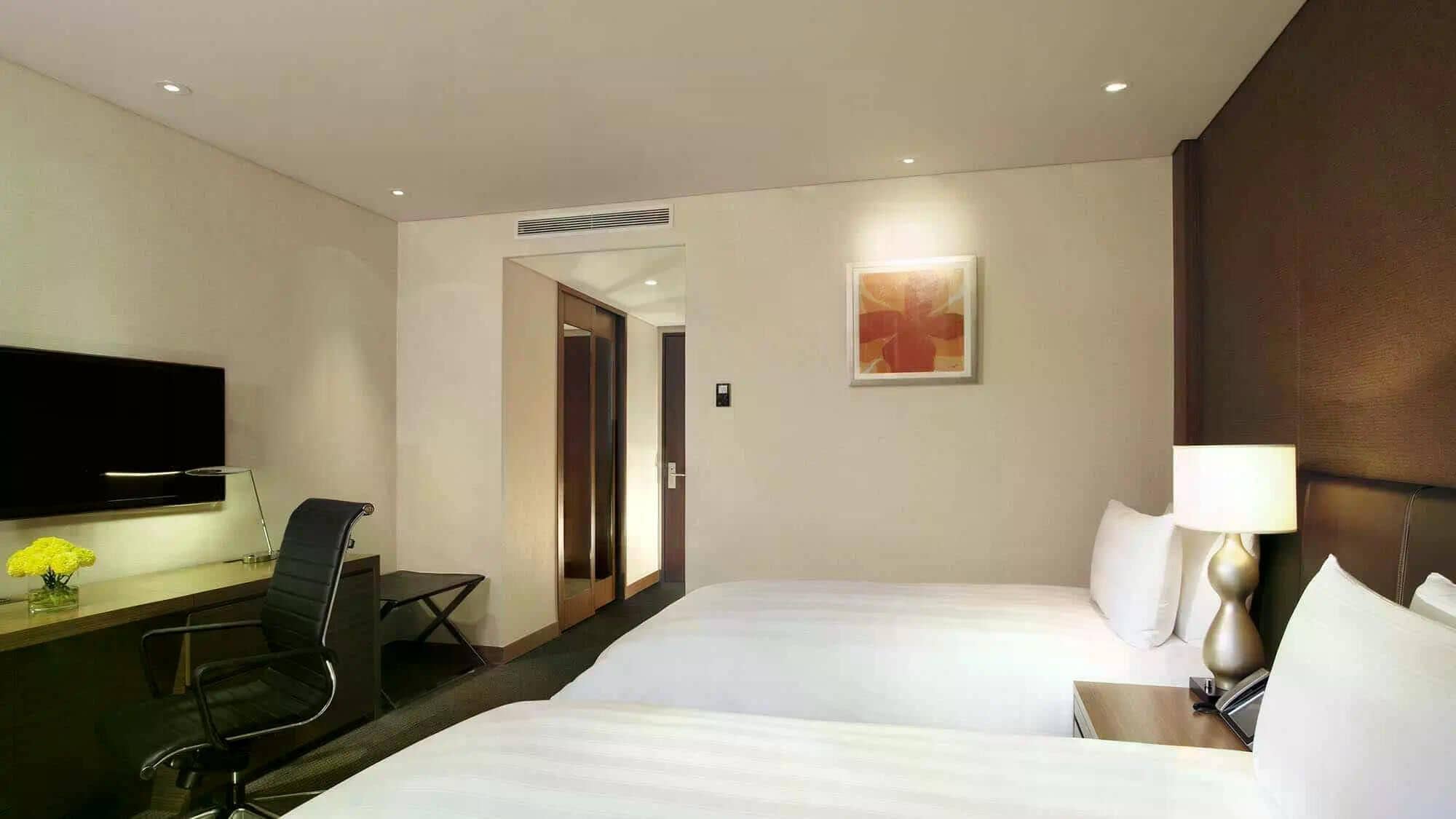 Ein Hotelzimmer mit Bett, Schreibtisch mit Stuhl, Fernseher und einem Bild an der Wand.