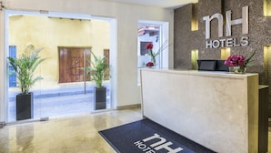 En hotellobby med en marmordisk, en receptionsdisk och ett område med en glasdörr som leder ut.