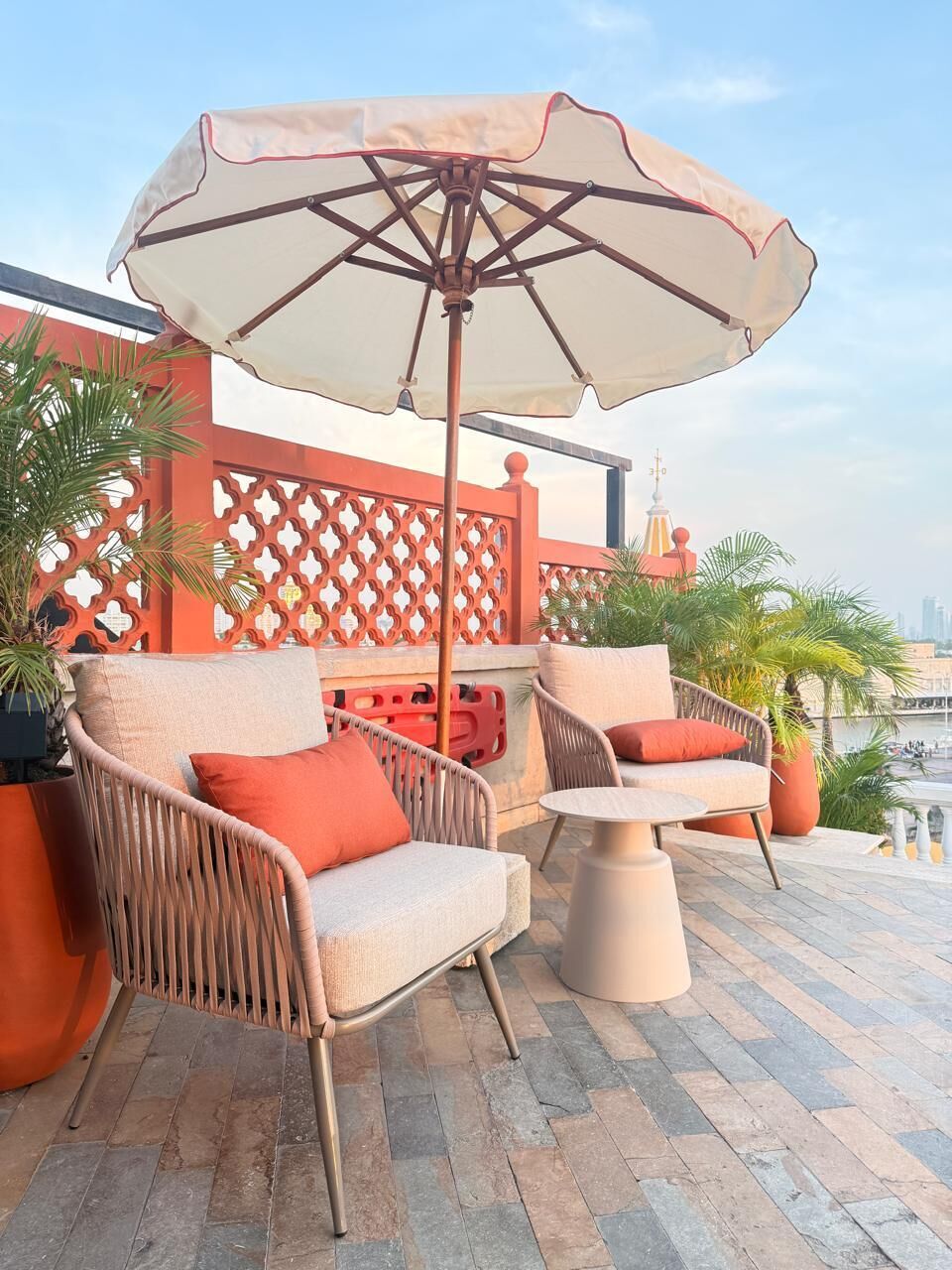 An outdoor seating area with wicker chairs, a table, and a large umbrella.