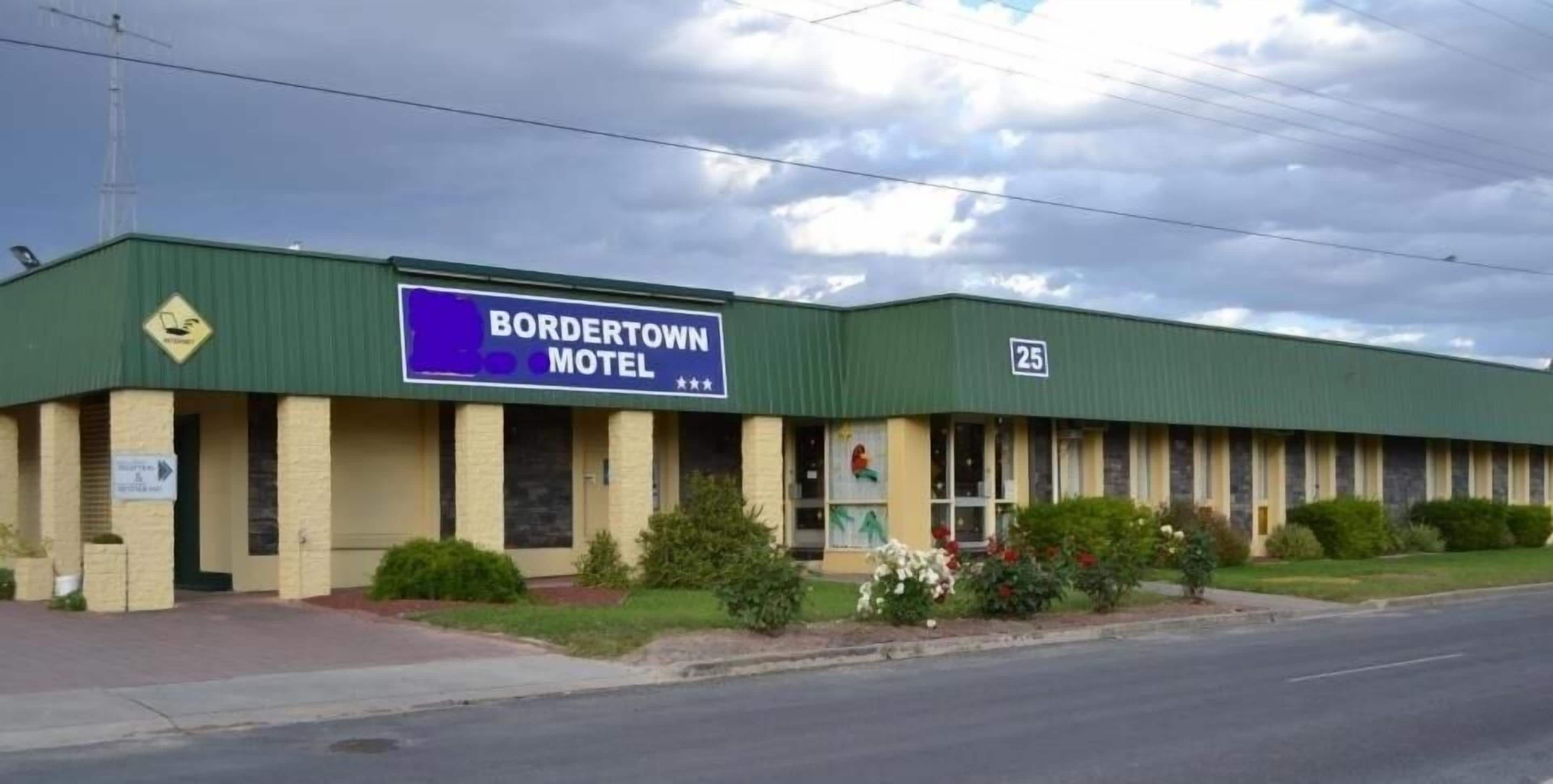 A motel named Bordertown Motel with a green exterior and a signboard.