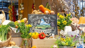 A display of fresh vegetables and fruits, including carrots, potatoes, onions, and bell peppers, with a chalkboard sign that reads "HOKKAIDO".