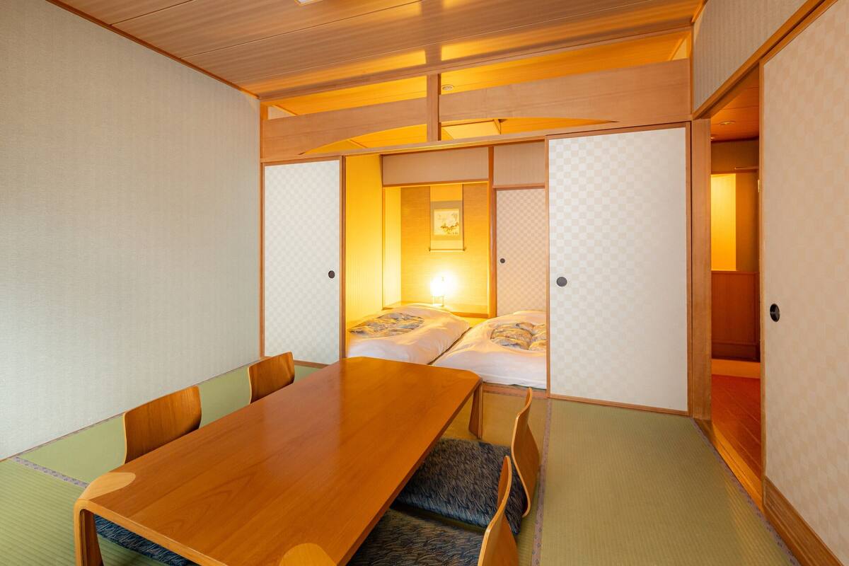 A traditional Japanese room with tatami flooring, a wooden table, and low seating.