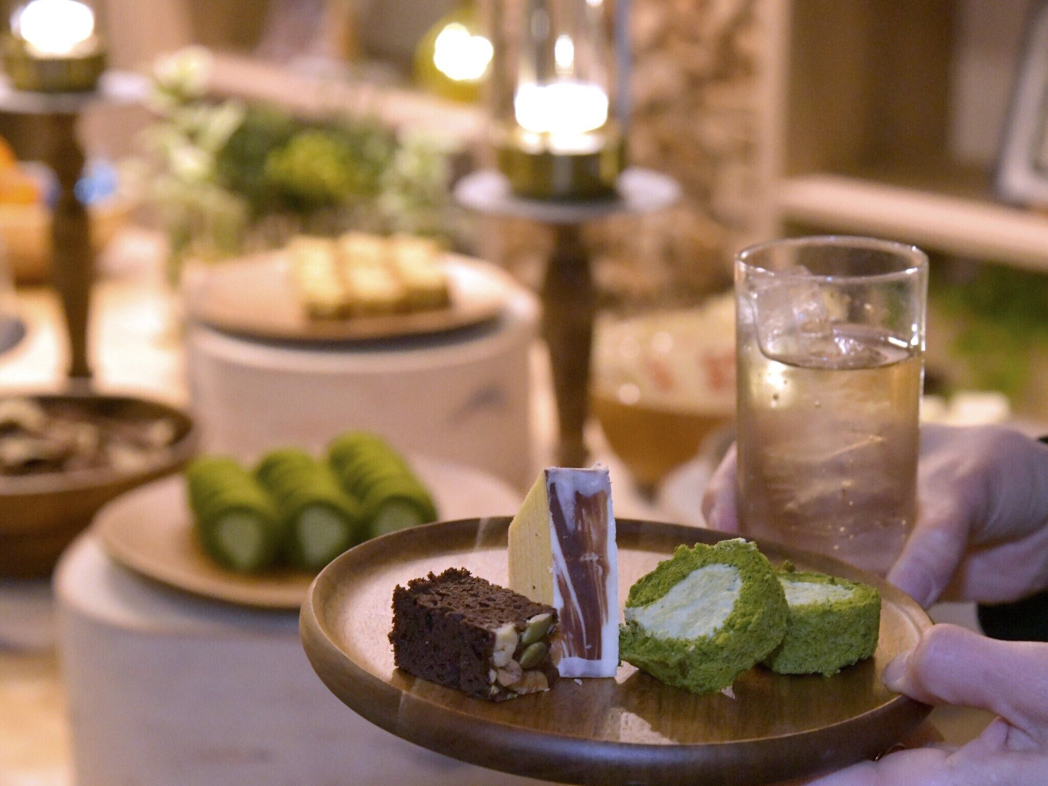 A dessert tray with various sweets and a glass of water.
