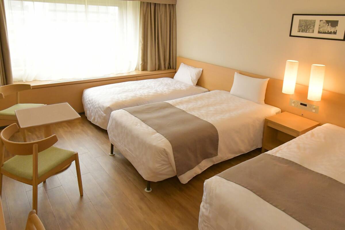 A hotel room with two beds, a desk, and a chair.