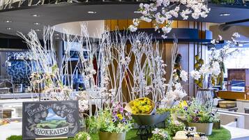 L’intérieur d’un restaurant est agrémenté d’un arrangement floral central, d’un menu écrit à la craie et de diverses plantes en pot.