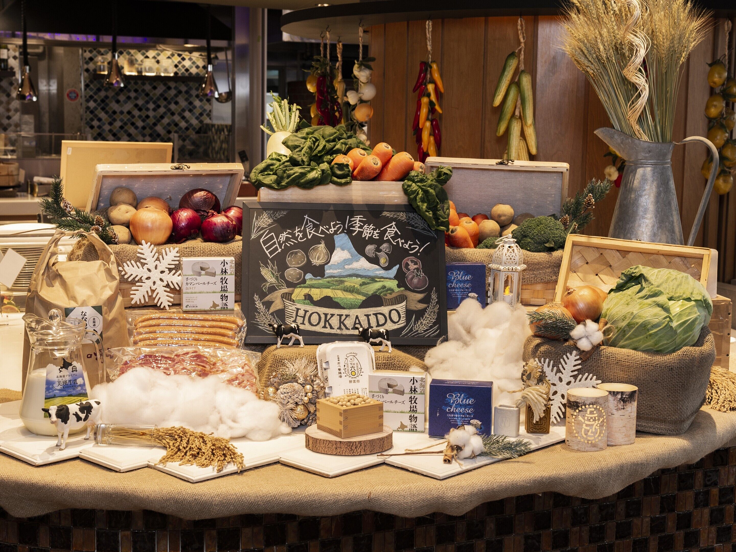 A display of various food items and dairy products, including cheese and vegetables, arranged on a counter.