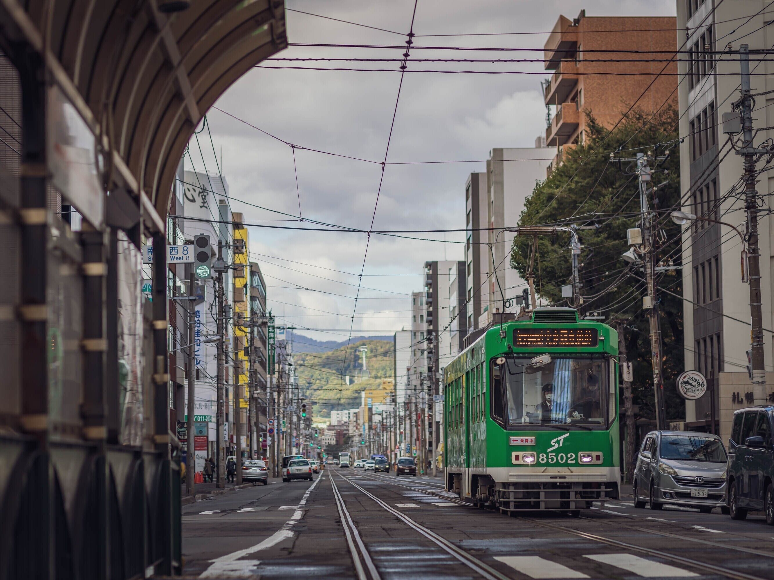 A tram on a city street with buildings and power lines.