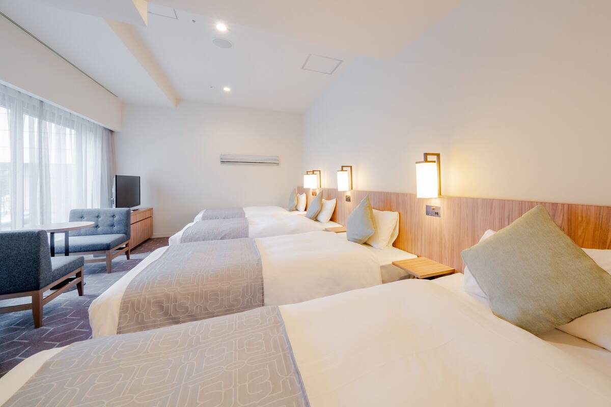 A hotel room with two beds, a TV, a desk, and a chair.