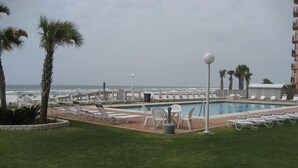 A pool area with lounge chairs and a view of the ocean. - Sunswept Condominiums (Orange Beach)