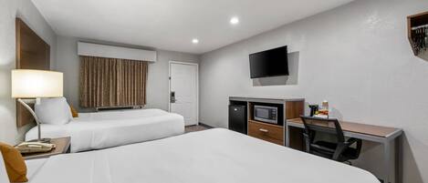 Quarto de hotel com duas camas, uma escrivaninha, televisão, micro-ondas e máquina de café.