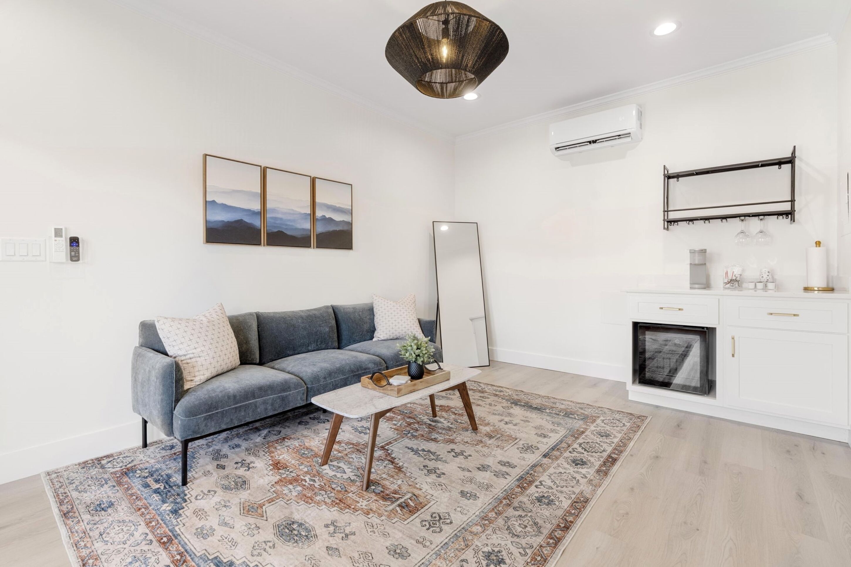 A modern living room with a grey sofa, a coffee table, and a patterned rug.