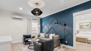 A modern living room with a blue accent wall, a grey sofa, a black armchair, and a round coffee table. - 27 On Park (Dahlonega)