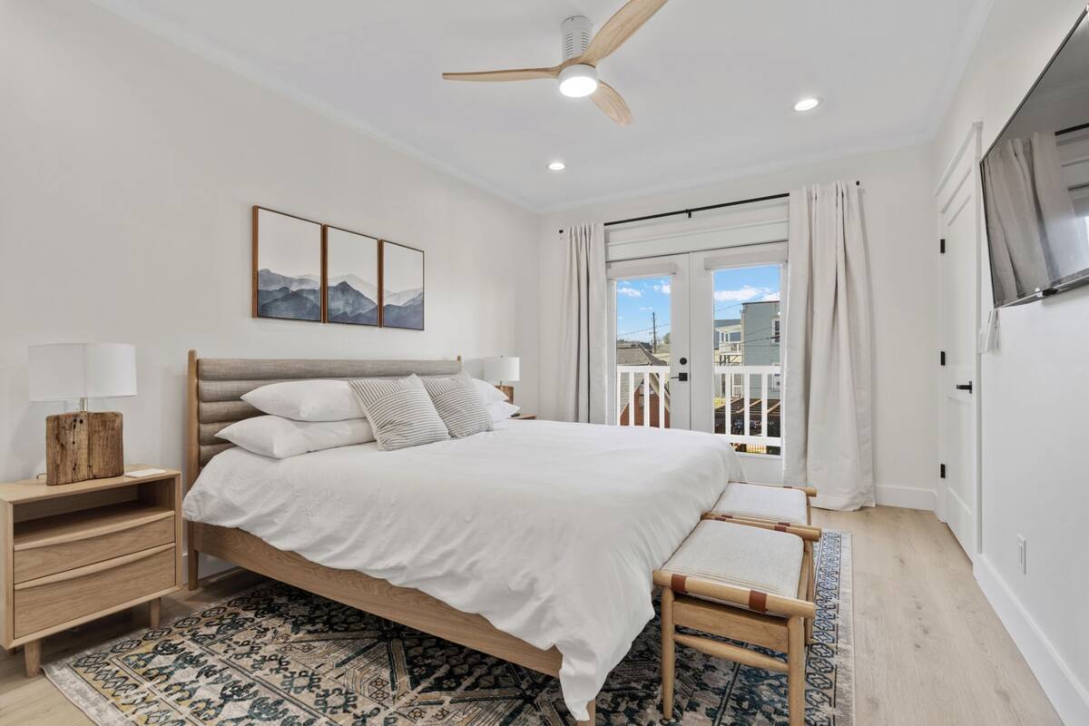Quarto com cama, mesa de cabeceira e vista para o exterior.