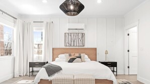 A bedroom with a large bed, bedside tables, a hanging light fixture, and a window with curtains. - 27 On Park (Dahlonega)