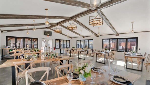 A spacious dining area with wooden tables and chairs, large windows, and hanging pendant lights. - 27 On Park (Dahlonega)