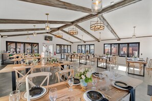A spacious dining area with wooden tables and chairs, large windows, and hanging pendant lights. - 27 On Park (Dahlonega)