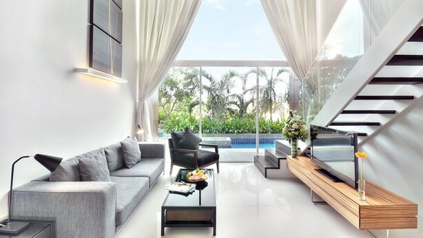 A modern living room with a grey sofa, black armchair, and a wooden coffee table. A TV is on a wooden console, and there's a large window with curtains. - Mida De Sea Hua Hin (Cha-am)