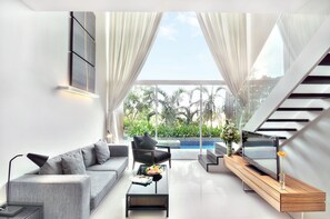 A modern living room with a grey sofa, black armchair, and a wooden coffee table. A TV is on a wooden console, and there's a large window with curtains. - Mida De Sea Hua Hin (Cha-am)