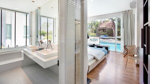 A modern hotel room with a large window, a private balcony, a pool, and a separate bathroom with a large sink. - Mida De Sea Hua Hin (Cha-am)