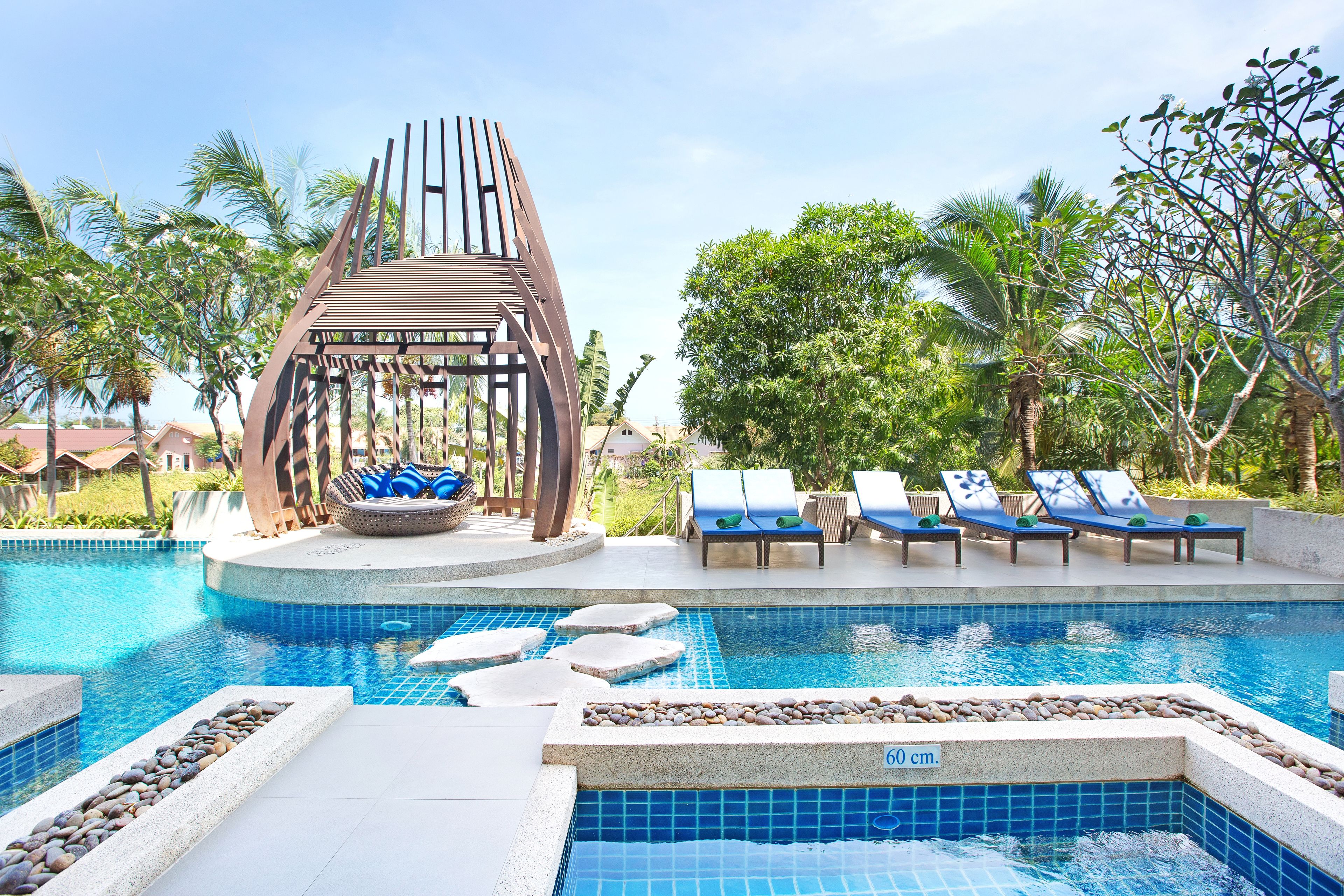 A pool area with lounge chairs, a decorative wooden structure, and a clear blue pool.