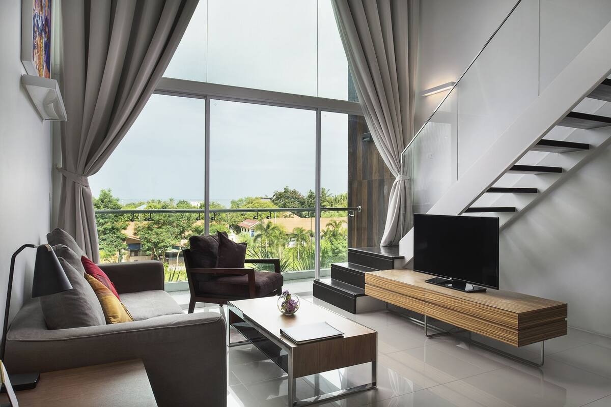 Una sala de estar moderna con sofá, mesa de centro, televisor y una escalera.