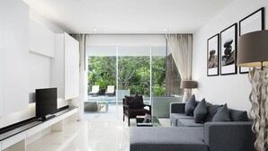 A modern living room with a flat-screen TV, grey sofa, and a glass coffee table. - Mida De Sea Hua Hin (Cha-am)