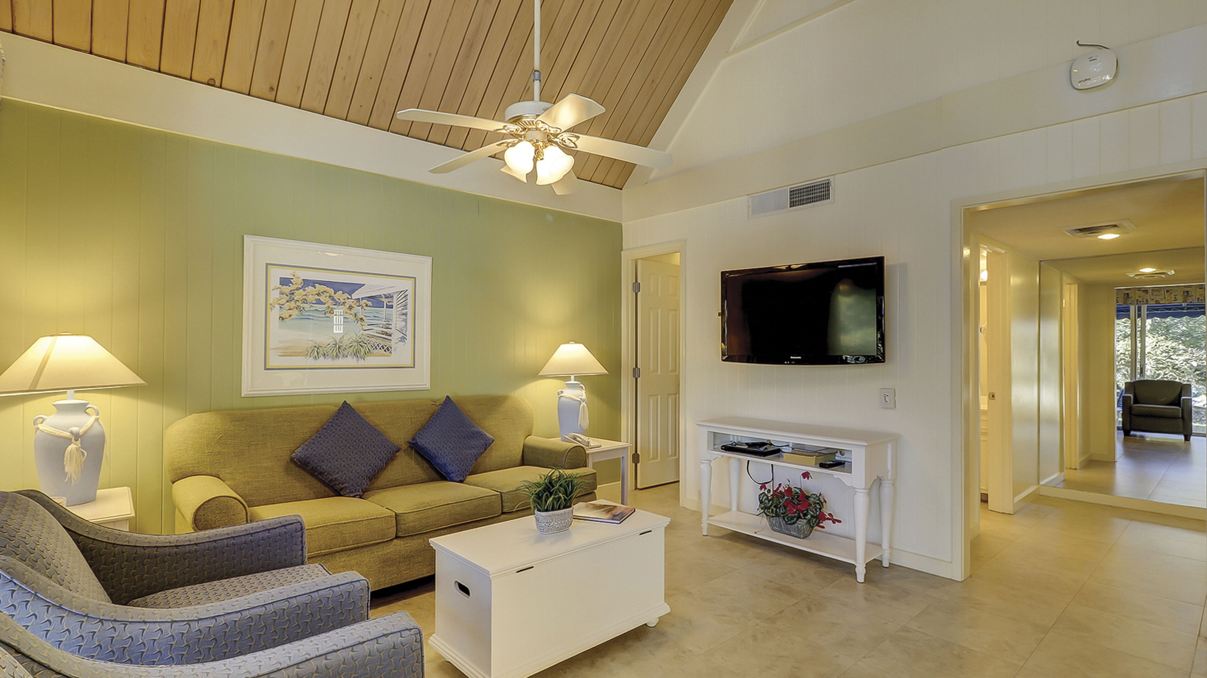 A living room with a sofa, armchairs, a coffee table, a fireplace, and a television.