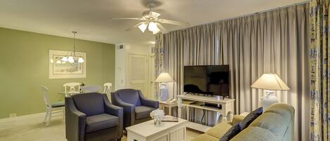 A living room with two armchairs, a sofa, a TV, and a ceiling fan.