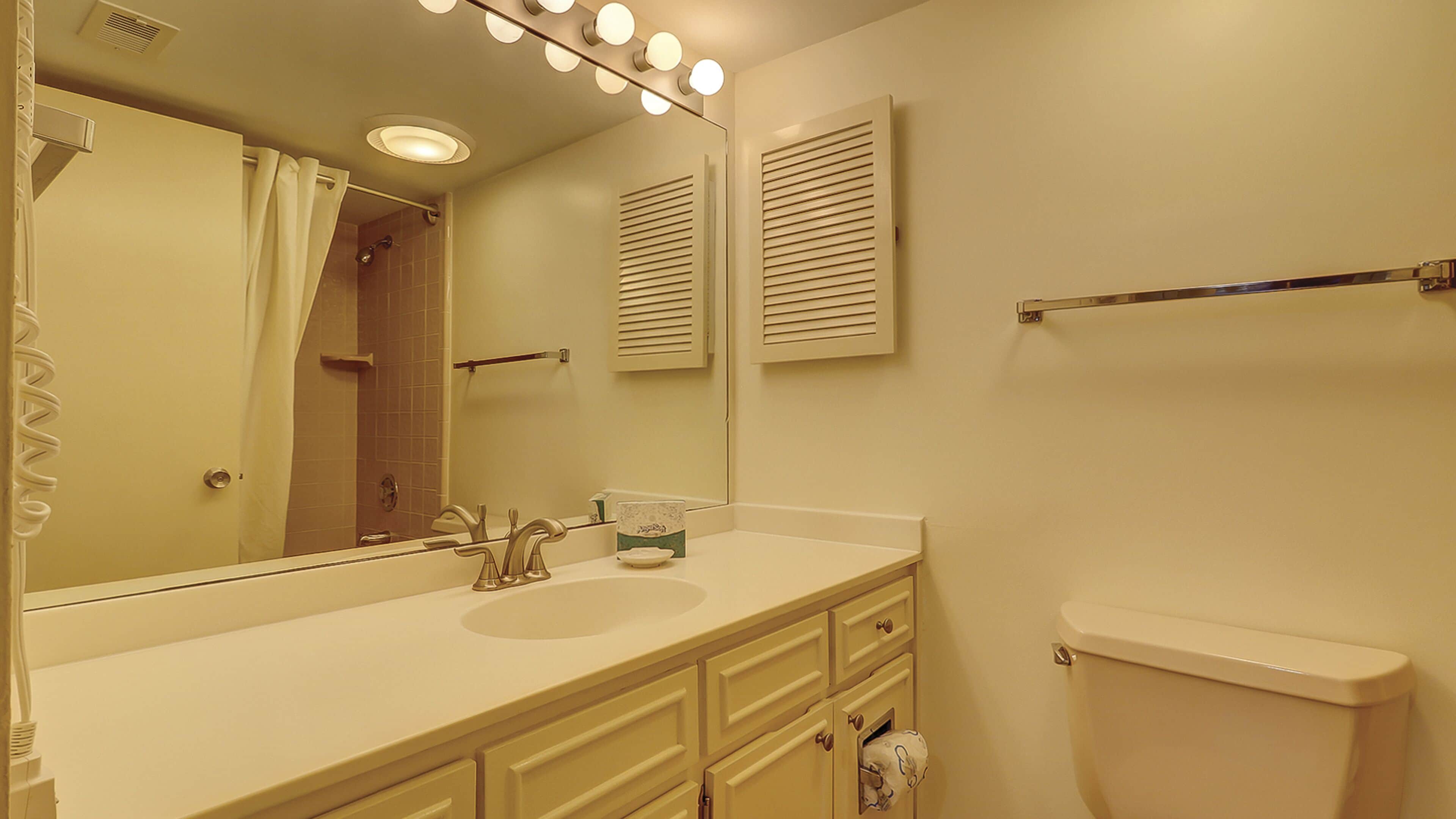 A bathroom with a sink, mirror, towel rack, and toilet.