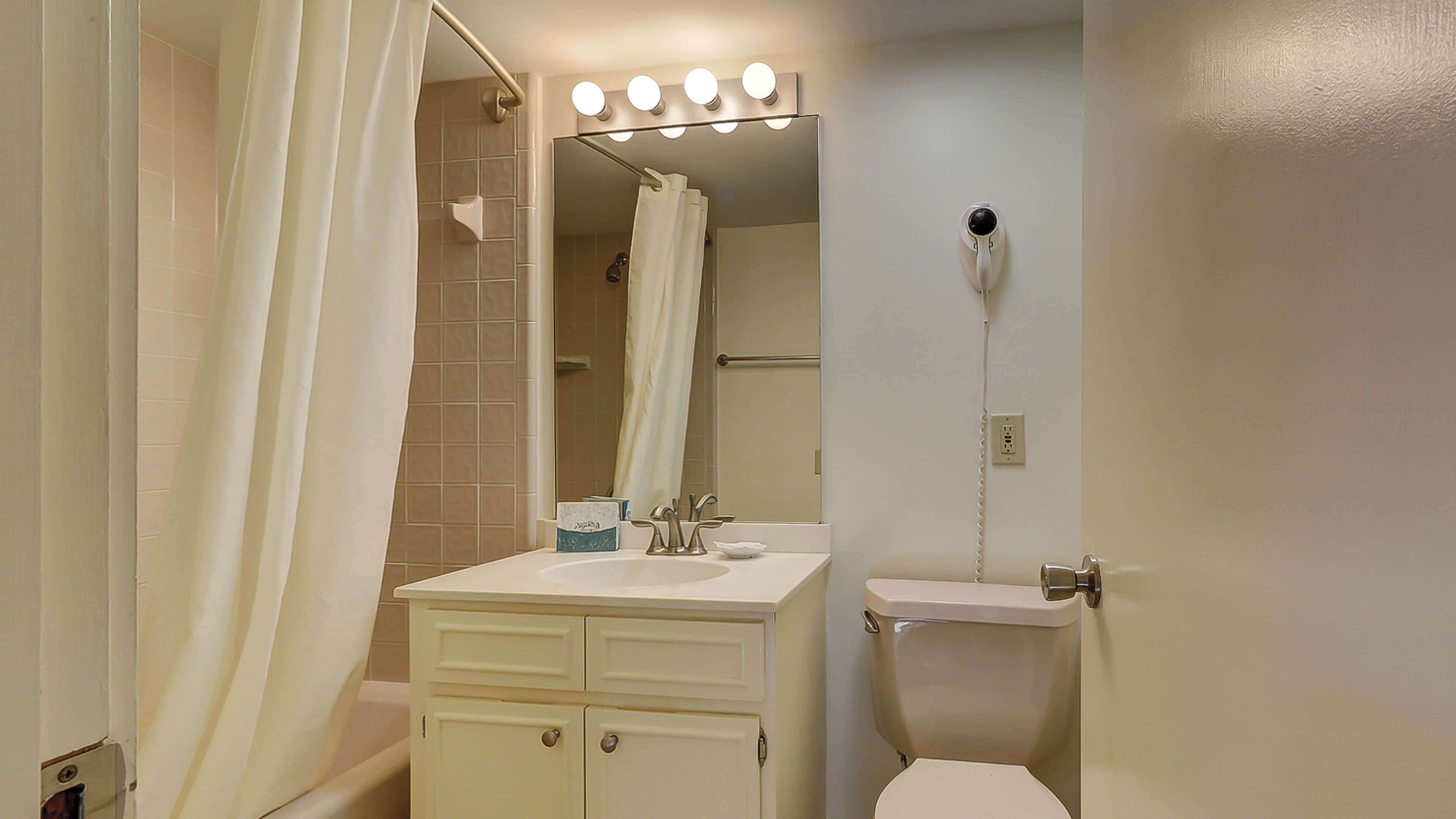 A bathroom with a shower, toilet, sink, and vanity.