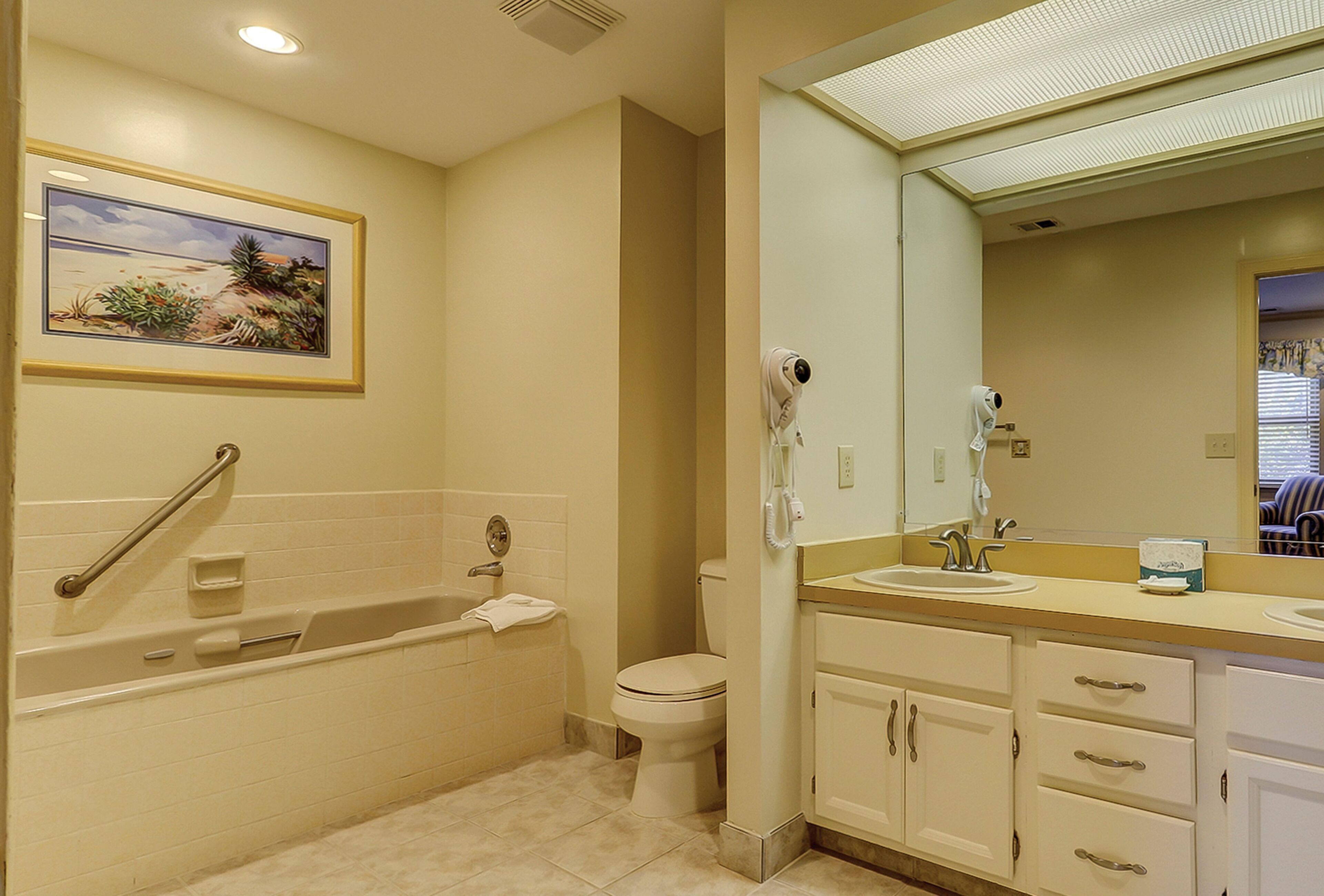 A bathroom with a bathtub, toilet, and vanity with a mirror.