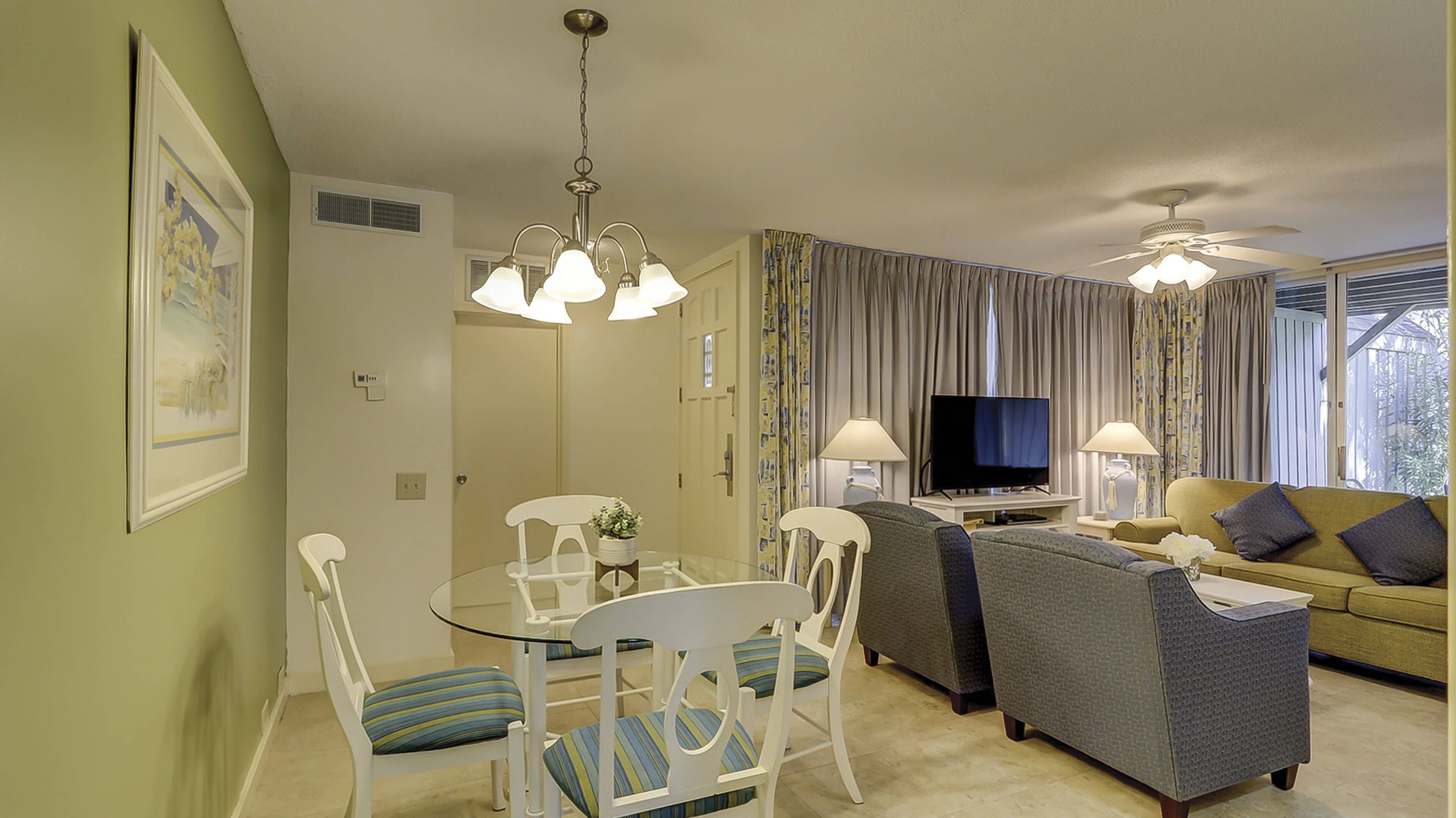 A living room with a sofa, TV, and dining area with chairs and a table.