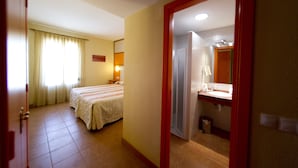 A hotel room with two beds, a bathroom with a sink and mirror, and a door leading to another room. - Hospedium Hotel Maestrazgo de Calatrava (Almagro)