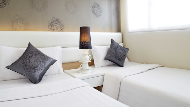 A hotel room with two beds, a nightstand with a lamp, and a patterned wall. - Bridal Tea House Hotel Yau Ma Tei Arthur Street (Kowloon)