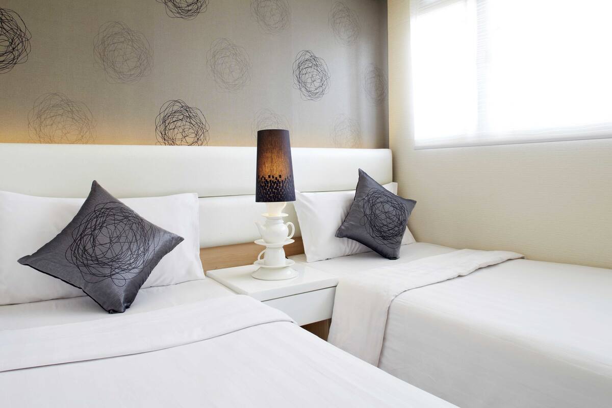 Ein Hotelzimmer mit zwei Betten, einem Nachttisch mit Lampe und einer Wand mit Muster.