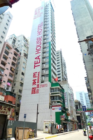 A tall building with a prominent vertical sign for the Red Tea House Hotel.