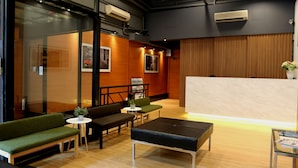 A modern reception area with a wooden reception desk, green seating, and a glass wall. - Bridal Tea House Hotel Yau Ma Tei Arthur Street (Kowloon)