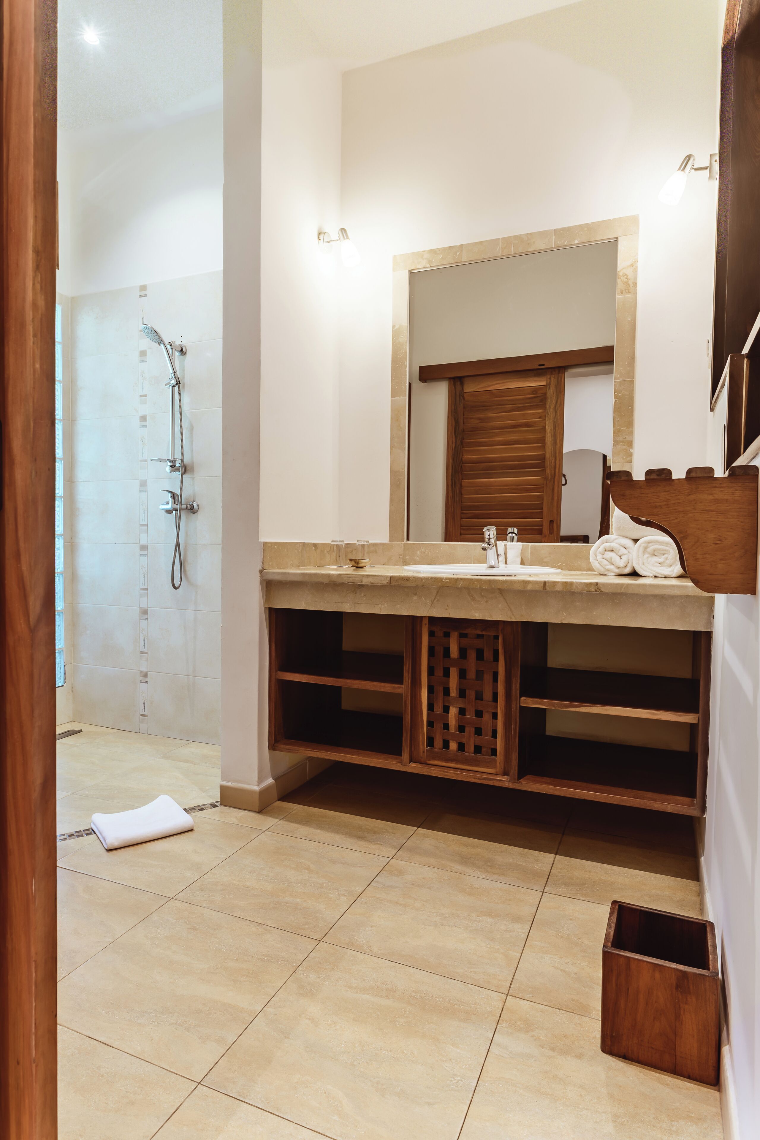 Une salle de bain avec une douche, un lavabo et un meuble-lavabo en bois.