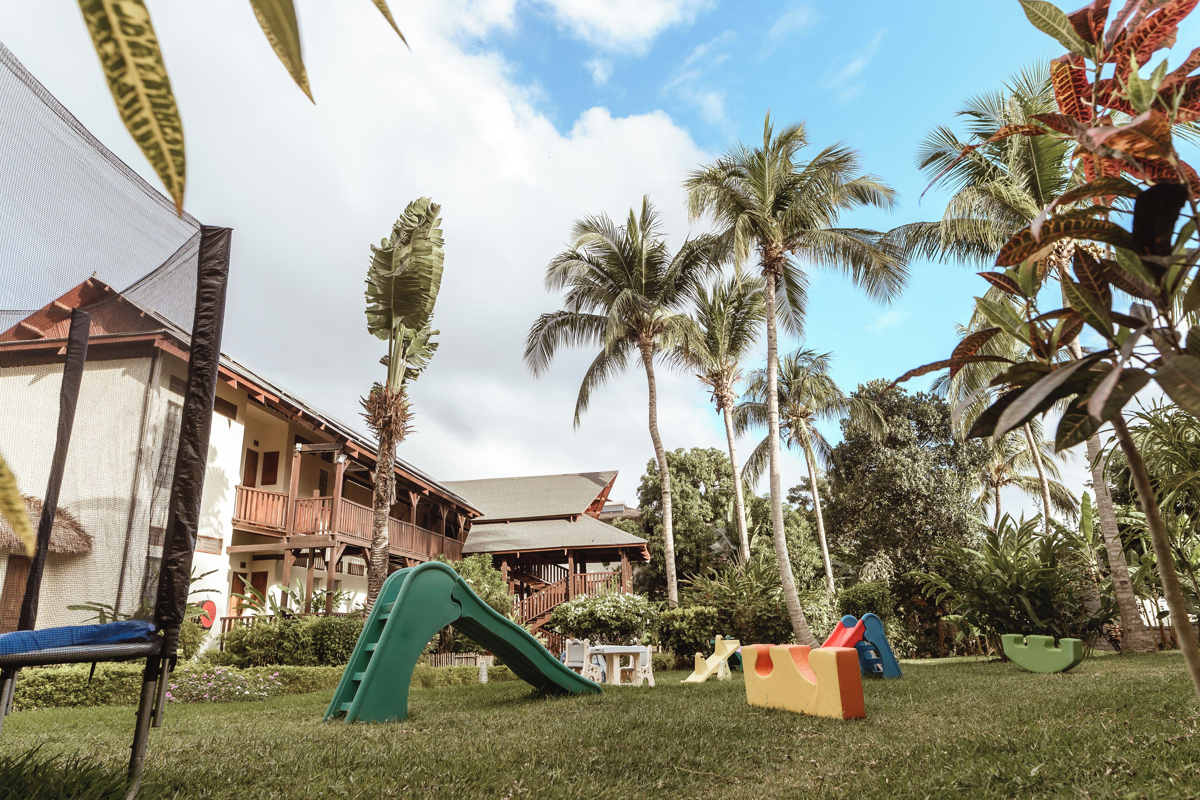A resort with a slide, palm trees, and a building with a balcony.
