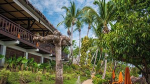 A tropical resort with a thatched-roof building, palm trees, and a pathway. - Vanila Hotel & Spa (Nosy Be)