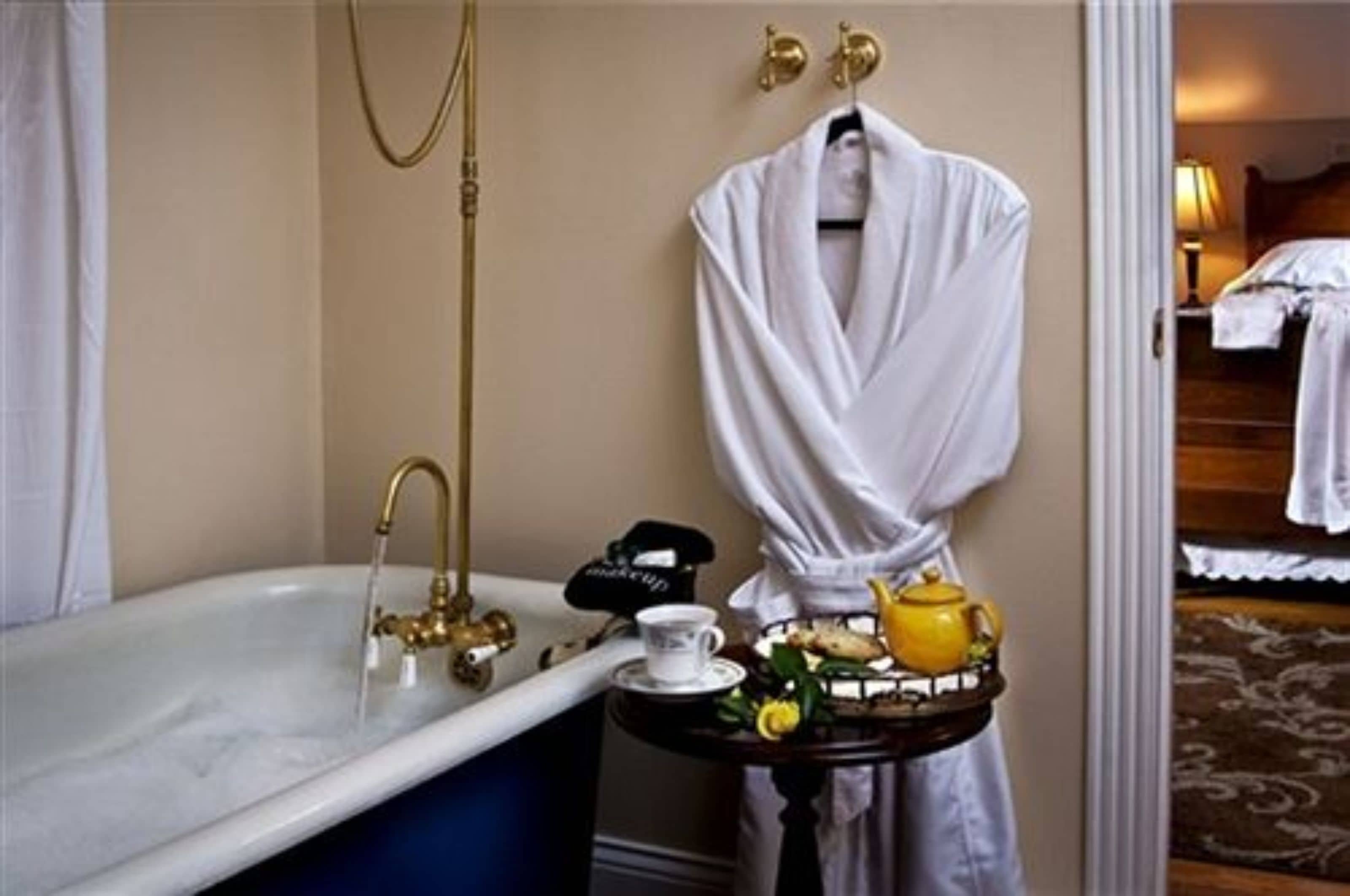 Ein Badezimmer mit einer Badewanne, einem Waschtisch mit Spiegel und einem Handtuchhalter.