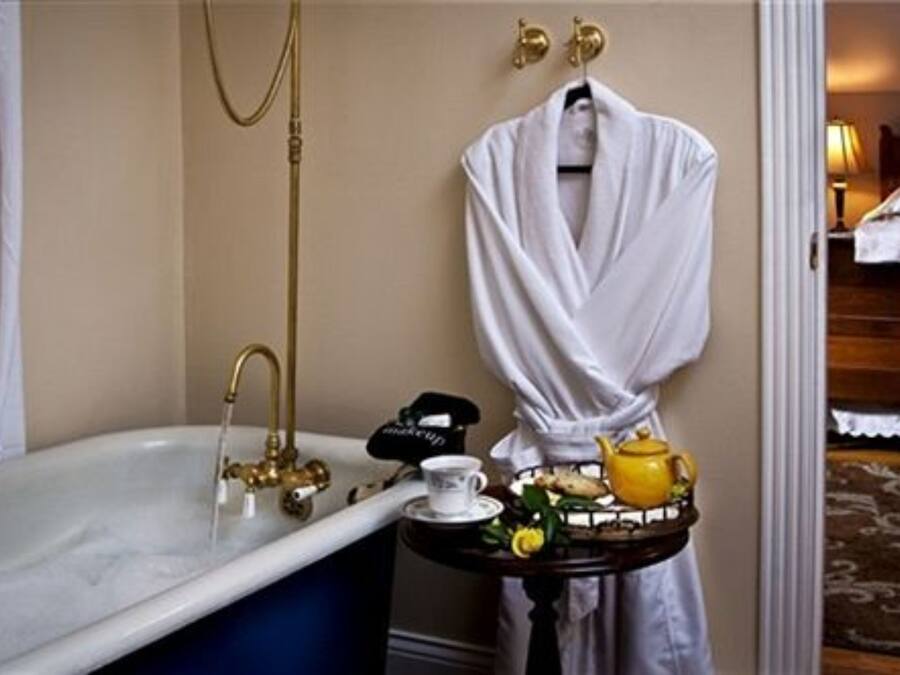 Ein Badezimmer mit einer Badewanne, einem Waschtisch mit Spiegel und einem Handtuchhalter.