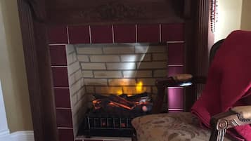 A fireplace with a brick surround, a mirror above it, and a chair with a floral pattern.