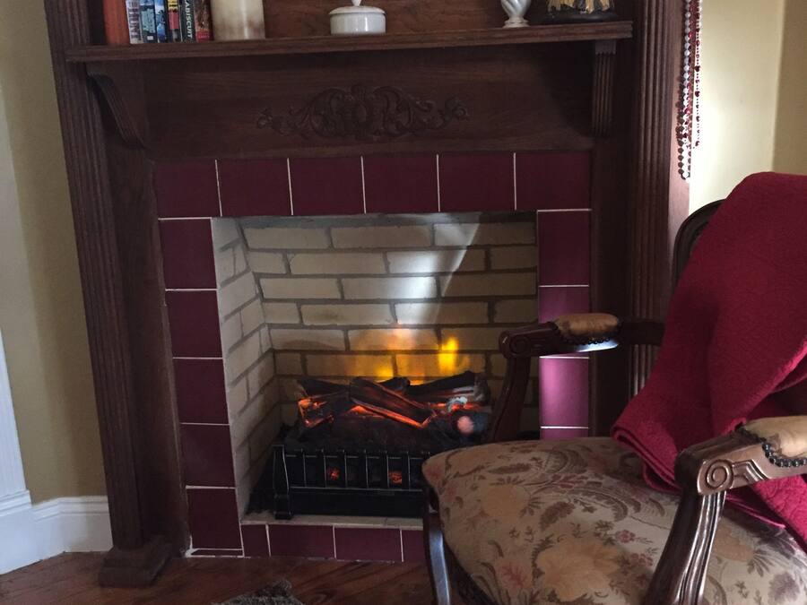 A fireplace with a brick surround, a mirror above it, and a chair with a floral pattern.
