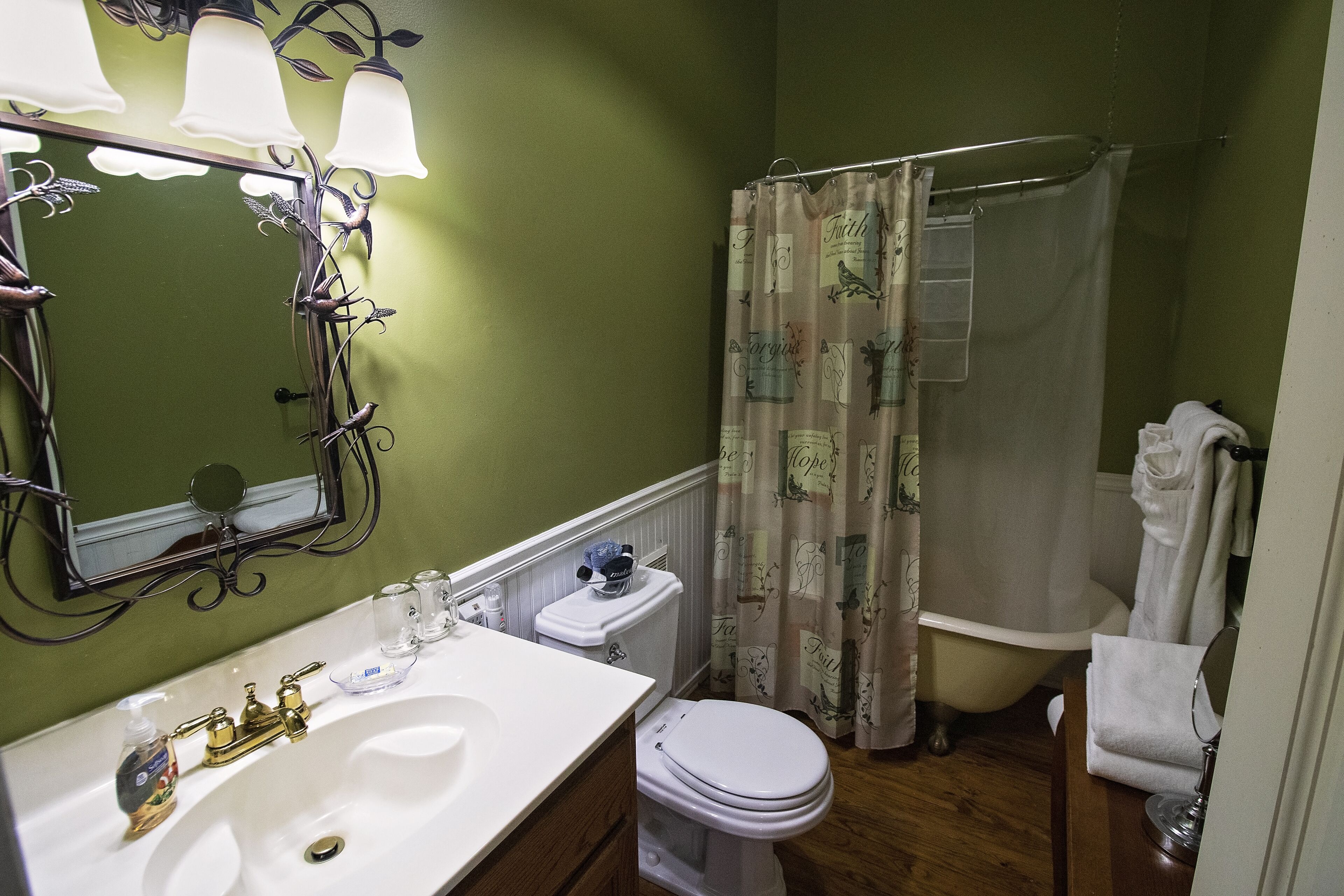 Une salle de bain avec un lavabo blanc, des toilettes, un rideau de douche et un miroir.