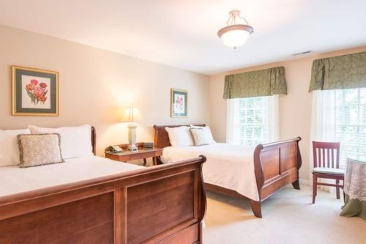 A bedroom with two wooden beds, a nightstand, a chair, and framed pictures on the wall.